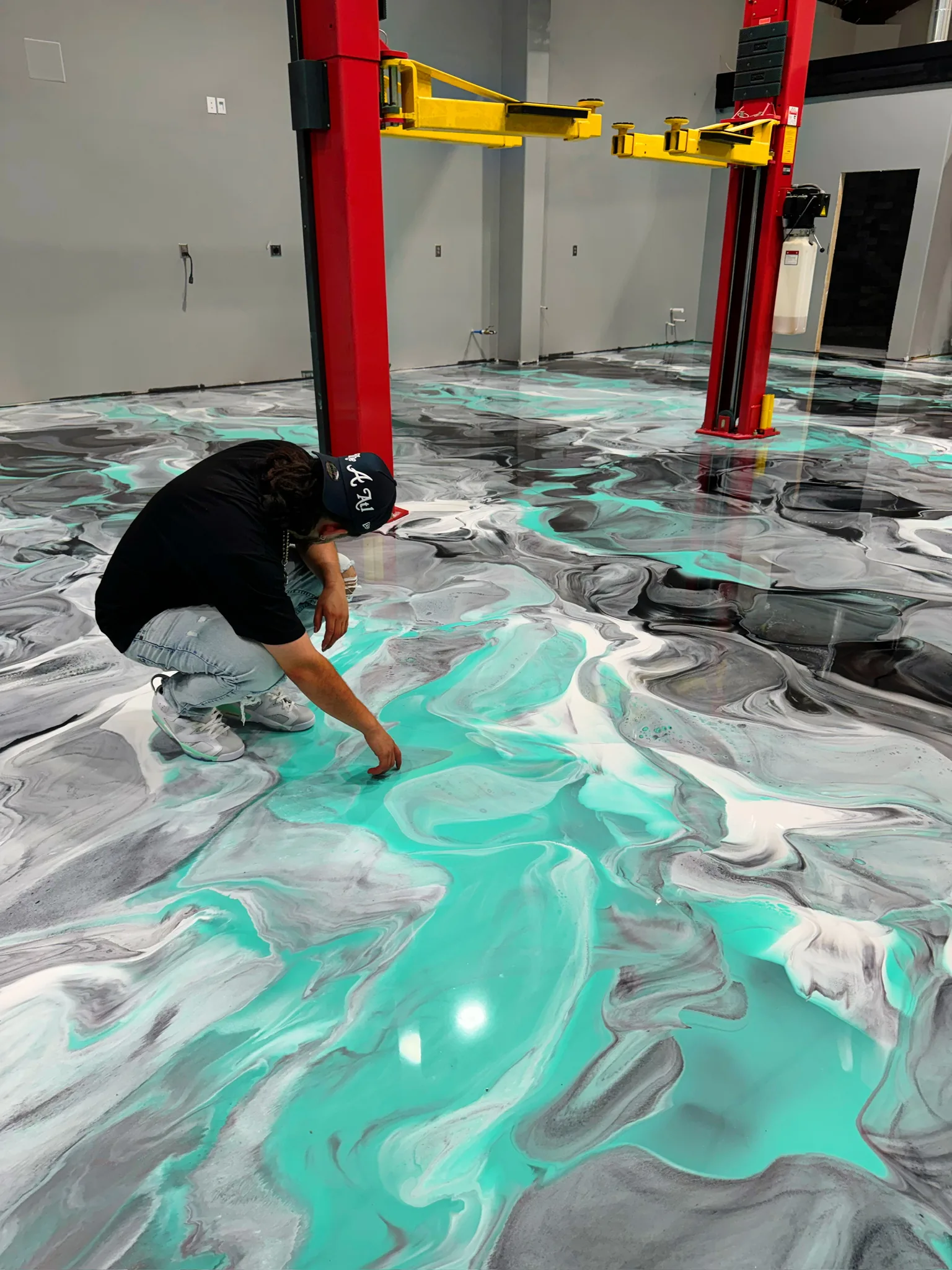 Metallic teal and pewter epoxy floor poured across a two-bay auto shop