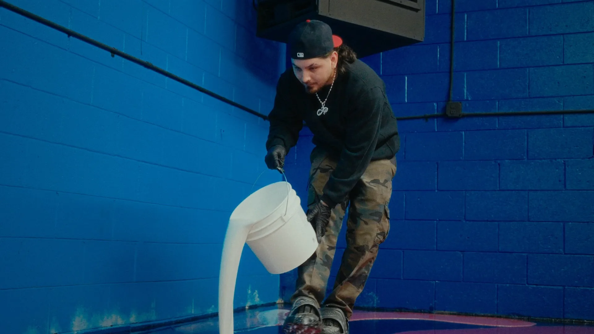 JP pouring resin against a blue block wall